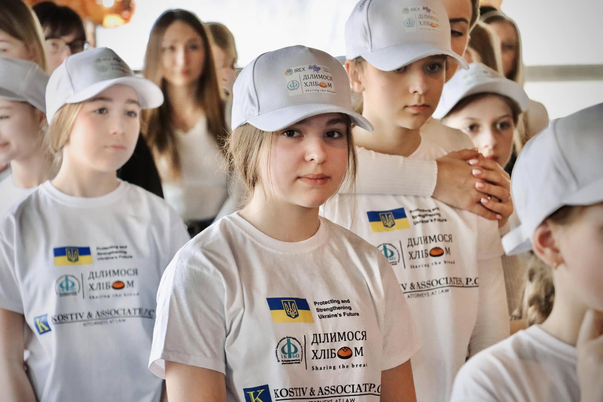 Діти у білих футболках посміхаються.